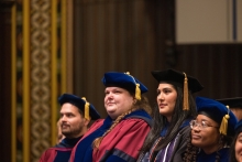 Picture of 4 graduates from a prior ceremony looking at stage.