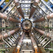 Many sets of pipes of varying sizes in a hexagonal shape, with a very small person up front showing the scale of the pipes.