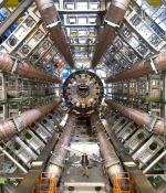  Many sets of pipes of varying sizes in a hexagonal shape, with a very small person up front showing the scale of the pipes. 