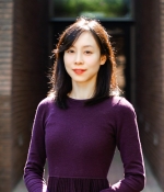  Xi Song, standing outside, posing in front of a door frame entrance to a building.  